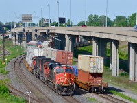 <b>Hot CN intermodals meet.</b> CN 120 and CN 149 are two of CN's highest priority trains. Here at Turcot West in Montreal we see the tail and head end of each. At left is CN 120 with CN 2293, CN 5482 & CN 5666, bound for Halifax. At right is the tail end of CN 149 which departed after being stopped by a red signal. Its destination is Chicago. Curving off to the left is the Lachine Spur and at right are the eastbound lanes of highway 20.