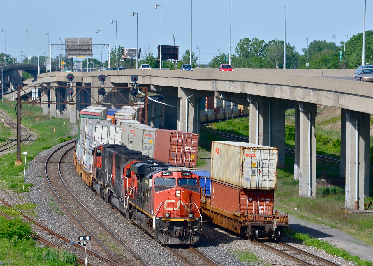 Hot CN intermodals meet. CN 120 and CN 149 are two of CN's highest priority trains. Here at Turcot West in Montreal we see the tail and head end of each. At left is CN 120 with CN 2293, CN 5482 & CN 5666, bound for Halifax. At right is the tail end of CN 149 which departed after being stopped by a red signal. Its destination is Chicago. Curving off to the left is the Lachine Spur and at right are the eastbound lanes of highway 20.
