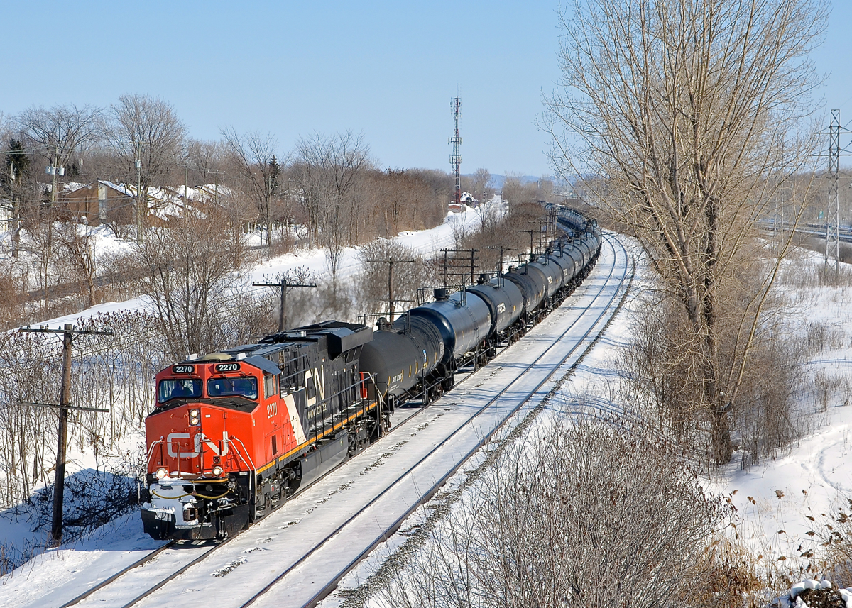 A late CN 305 with CN 2270 at the head end and CN 8021 mid-train heads west through Beaconsfield on Montreal's West Island.
