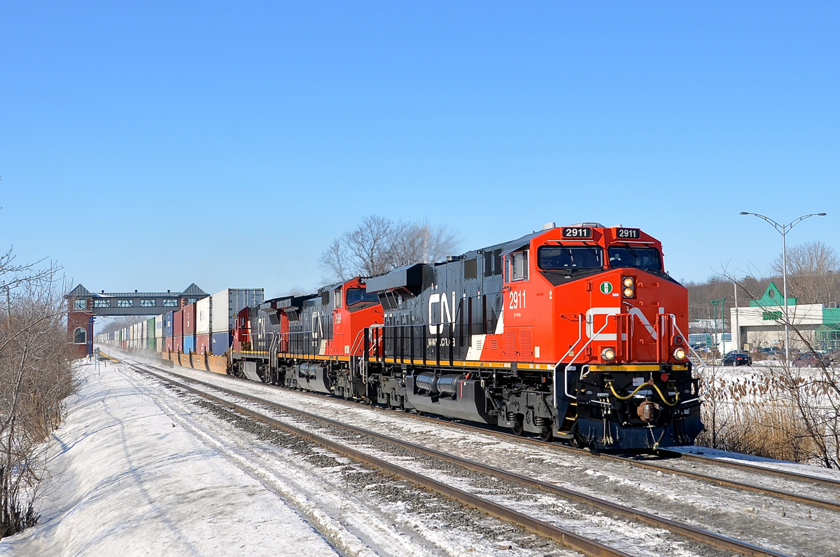 A fresh leader. A trio of GE's (CN 2911, CN 2689 & CN 2102) blast past the Saint-Basile-le-Grand AMT station with CN 120 for Halifax. Leading is a brand new GE ES44AC.