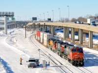 CN 120 with CN 2302 leading two ex-UP C40-8's (repainted CN 2004 and yellow CN 2001) heads east through Turcot West in Montreal. It is passing some MoW personnel who are at the switch for the Lachine spur (at left).