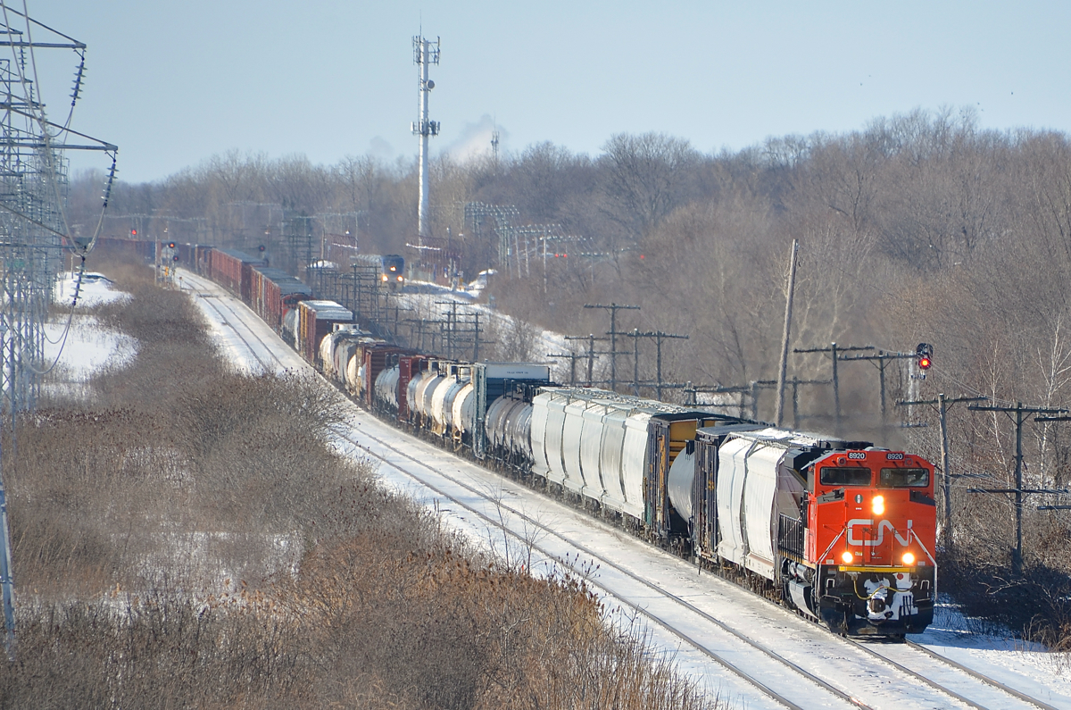CN 368 has 640 axles total as it passes through Beaconsfield with shiny CN 8920 leading and another SD70M-2 mid-train. In the distance at right is an AMT train on the parallel CP Vaudreuil Sub.
