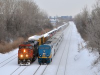 Both CN 527 (with CN 5518) and VIA 67 (with VIA 909) are moving as VIA 67 prepares to overtake CN 527, which is only doing a few miles per hour. Soon CN 527 will enter nearby Taschereau Yard.