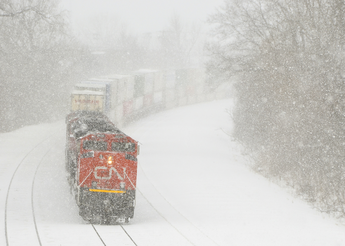 Limited visibility. CN 120 is partially obscured by blowing snow as it heads east with CN 8926, CN 8876 & CN 5657.