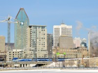 <b>Towards downtown Montreal.</b> AMT 1354 is pushing AMT 809 towards Montreal's Central Station at the tail end of the morning rush hour. In the background is downtown Montreal, including Place Ville-Marie, the tallest building behind the second coach.