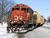 CN 4136 crosses Front Street pushing three hopper cars towards the elevator in Sarnia while the driver in a gold mini van plays chicken.