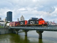 CN 7031 and CN 7256 shove a decent sized cut of grain cars east through the old port of Montreal. The train is crossing over the eastern end of the Lachine Canal and is about to curve to the east. In the distance at right is the ship "Algoma Montrealais".