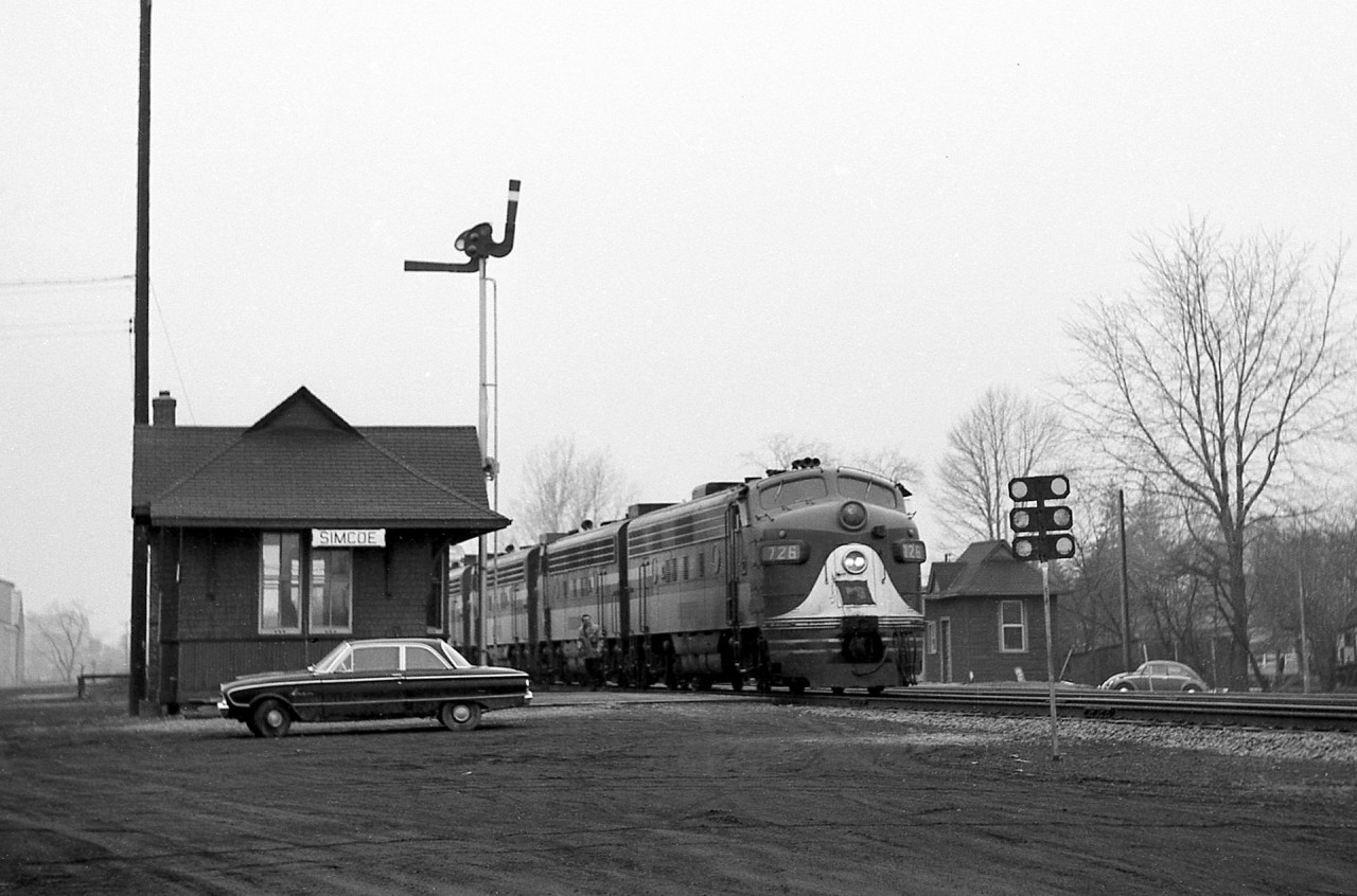 An eastbound Wabash Railroad train with a healthy lashup of F-units (WAB F7A 726 in the lead position) stops on a red board at the Canadian National station in Simcoe ON (Mile 73.2) on CN's Cayuga Sub.Part of the former Great Western Railway "Canada Air Line", service through Simcoe ended when CN abandoned the line from Mile 54 to 82 in December 1995. The station pictured is a replacement station built in 1930/31, after the original was destroyed by fire in July 1930.Canadian-built Wabash F7A 726 (originally numbered 1189A, blt. March 1952, serial A488, order C157) would later go on to work for Norfolk and Western as their N&W 3726, seen here at Thamesville ON 10 years later: http://www.railpictures.ca/?attachment_id=18006
