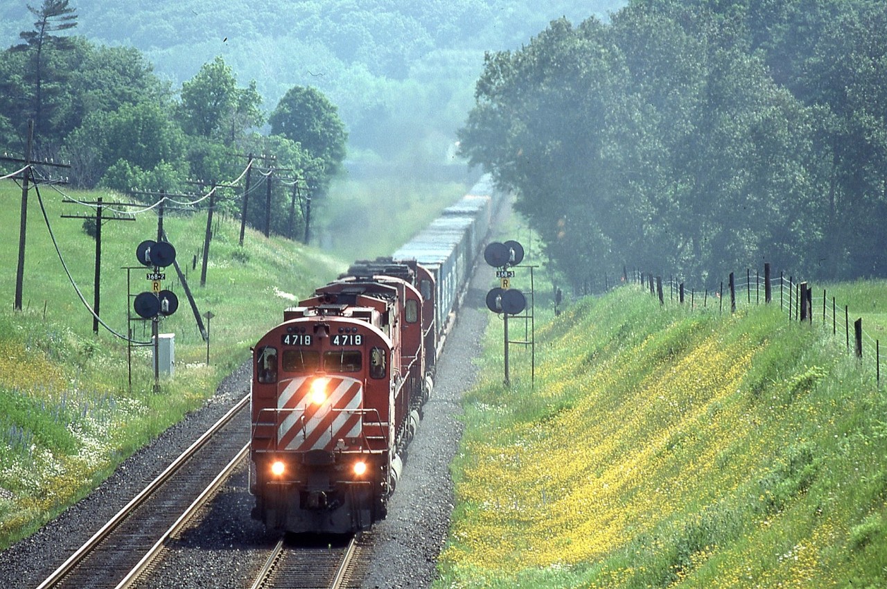 I'm standing on the horse bridge over the Galt Subdivision on a humid June morning in 1993 waiting to see what may come my way.

I didn't have to wait long as train 509 with three 4700's (4718,4735,4704) called the RTC for a clearance passing by the Glen Eden ski hill to continue it's journey west. The train rounded the curve a minute later and provided me with this amazing scene.

While this location has changed a little over the years gone are the 4700's and the Kodachrome I shot them on.