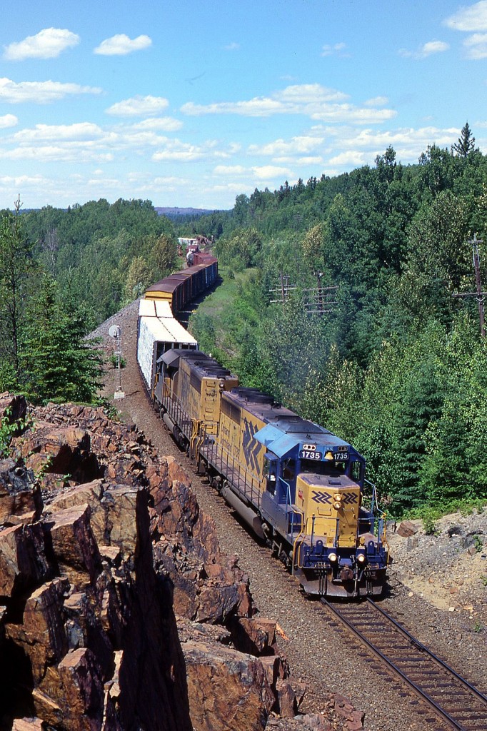 I, like so many others, have always enjoyed Ontario's accessible northern areas. However, in the past years since the province has gone rampant with their gasoline taxes, I have made fewer and fewer trips. And the fabled historic mining area around Boston Creek I've not seen for close to 10 years. It is a shame. If prices stay lower, maybe I'll gas up and head back this spring, before another gas tax (carbon)gets slapped on....Well, enough of the soapbox. In this view, southbound ONR 1735 and 1731 pull a rather lengthy train from, I assume, Cochrane; and this view from the edge of the rock cut here makes for a nice image. In the distance, not visible, is the Adams Spur, connection to former Adams Mine, a location Toronto was once interested in dumping their garbage at. Fortunately, this asinine idea was never approved. The ONR 1735 is still rolling, but 1731 was sold in 2005 and now toils out in Saskatchewan for a private company.