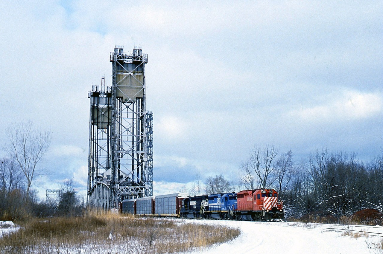 I have submitted a photo or two from this location before, but I feel this image best shows the scene from Hayes Rd (named for the Hayes-Dana plant that this road once led to)looking toward Bridge 10 over the Welland Canal and the City of Thorold. Due to work being done on CN's Bridge 6, CN Grimsby Sub, in the early winter of 1996/97 a handful of St. Thomas/Buffalo NS #328 trains were rerouted down from the CN connection at mile 9.49 (Merritton Sta) to Bridge 10 over the canal on the Thorold Sub and down to connect the CN Stamford sub at Port Robinson. The trains were rerouted only if they were later than approximately 10am. Once AMTK #97 cleared thru around 10 AM the work block went up. I know of only about 5 reroutes. So this was a rare catch; even more so because not long after this, Bridge 10 was deemed redundant and dismantled. The former CN line on the west side of the canal is now used by Trillium, and on the east side, the trackage from Port Robinson connects with Resolute, the big forestry plant in Thorold South. The track in this photo was pulled up a number of years ago as well. Power on this #328 is CP 5521, GATX 7371 and NS 6215. The view at this location today is just field and weeds. One would have to consider this an alternate route to alleviate the bitching and complaining by the mayor of Niagara Falls in regards to CN trains breaking down passing thru the city; that is, if the bridge and track had only been left in place. Much shorter route, too.