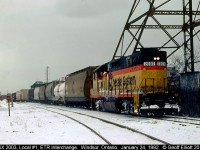 CSX GP38 #2003 has charge of Local #1 today as the snow falls January 24th, 1992.  Local #1 has just setoff a cut of cars into the ETR interchange track and is pulling out to double back onto their caboose before leaving town.  The old Dominion Bridge tower is still standing to the right in this picture which most people from the Windsor area will be familiar with.