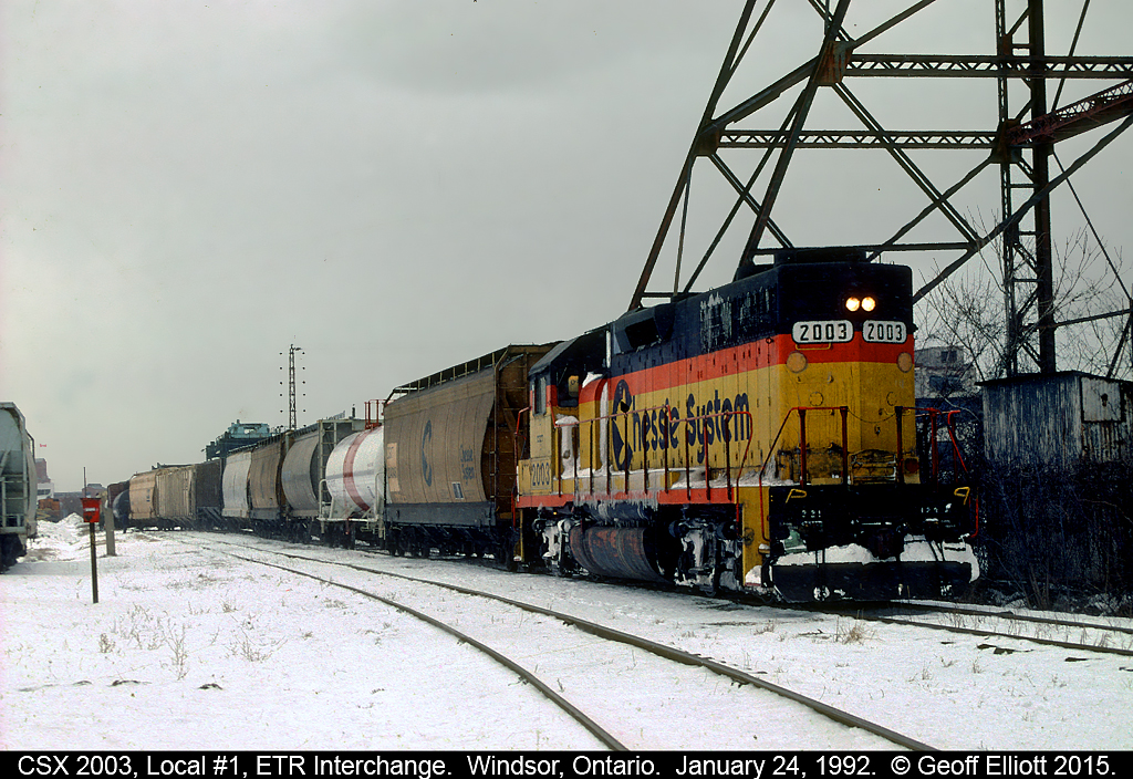 CSX GP38 #2003 has charge of Local #1 today as the snow falls January 24th, 1992.  Local #1 has just setoff a cut of cars into the ETR interchange track and is pulling out to double back onto their caboose before leaving town.  The old Dominion Bridge tower is still standing to the right in this picture which most people from the Windsor area will be familiar with.