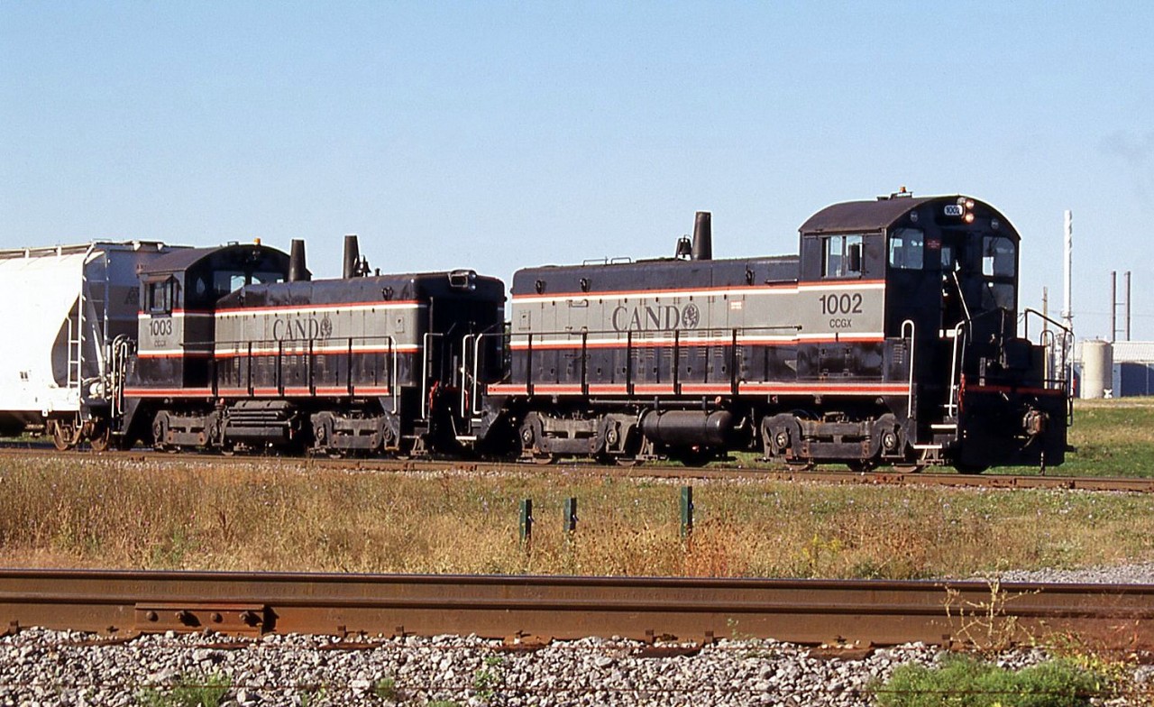 Cando Contracting SW8M 1002 and SW1200 1003 are seen switching the Invista plant coupled nose-to-nose, at Millhaven, Ontario. Invista was fibre manufacturer, formerly KOSA and before that Celanese. Their Millhaven plant, located 10 miles west of Kingston, ceased production in April 2000 and was demolished in 2013.

Invista was located on CN's Millhaven Spur, 1.5 miles in from the Kingston Sub switch at Mile 186.6. CN switched the plant for many years, but Cando was later contracted to do the job. With Invista gone Cando continues to do contract switching for the neighbouring Coco Paving asphalt plant.

According to the CTG, CCGX 1002 was originally built as Lehigh Valley SW8 in September 1951, and CCGX 1003 was originally built for the Pennsylvania Railroad as SW1200 7921. Both were acquired by Cando from dealer Andrew Merrilees in 1996.