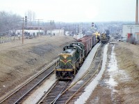 A pair of Canadian National MLW RSC-13's (lead by 1716) head east with a short train at Georgetown ON, on CN's "new" Halton Sub, which had only existed for a few months since the January reorganization. A few cars back is a large dimensional load, which appears to be an earthmover known as a scraper. To the right, a GMD SW1200RS works on the lead to the local Georgetown industries and yard, today used by GO Transit to store and load trains.
<br><br>
The pointed spiral of the station is visible in the background above the train, and further in the distance are the signals for Silver, where the Guelph Sub (formerly part of the Brampton Sub just a few months earlier) branches off from the Halton (made up of parts of the former Brampton and Milton Subs, plus a new section to Toronto (MacMillan) Yard).