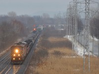 BCOL 4603 and CN 2435 head west on the south track of the Kingston sub on a rainy evening with CN X321. At left is the headlight of CN 373 (with CN 2229 and CN 2290), also heading west at the same time.