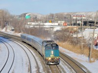 VIA 69 has left the island of Montreal but is already 25 minutes late due to a late departure from Central Station. Here it passes through Montreal West with VIA 6440 leading. In the background are mountains of snow collected by the city.
