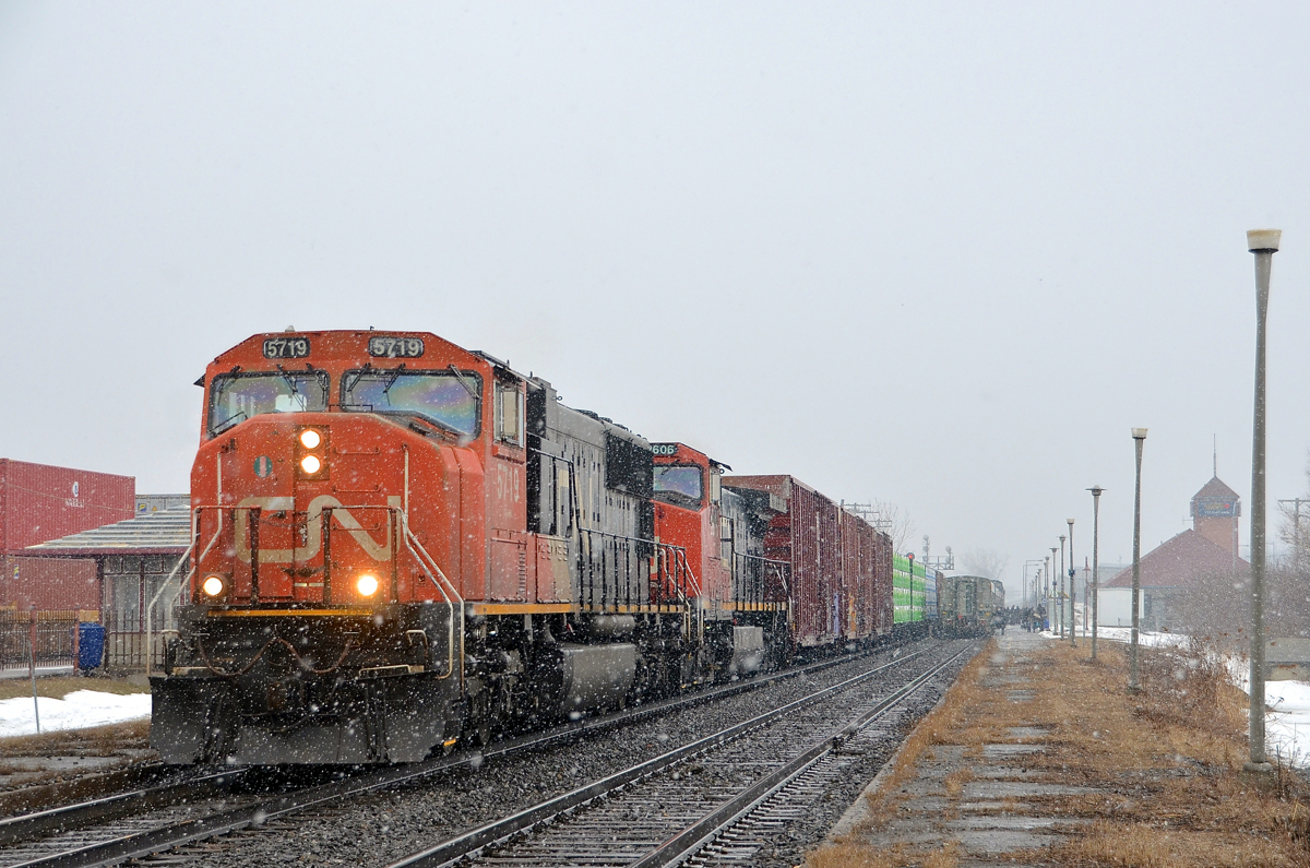You call this spring? CN 327 has CN 5719 and CN 2606 as it heads west past the VIA Dorval Station at right and the AMT Dorval Station at left. At left is CP 112 heading towards the Lachine intermodal yard and stopped at right is a late VIA 62. Quite a bit of snow is falling on the first day of spring.