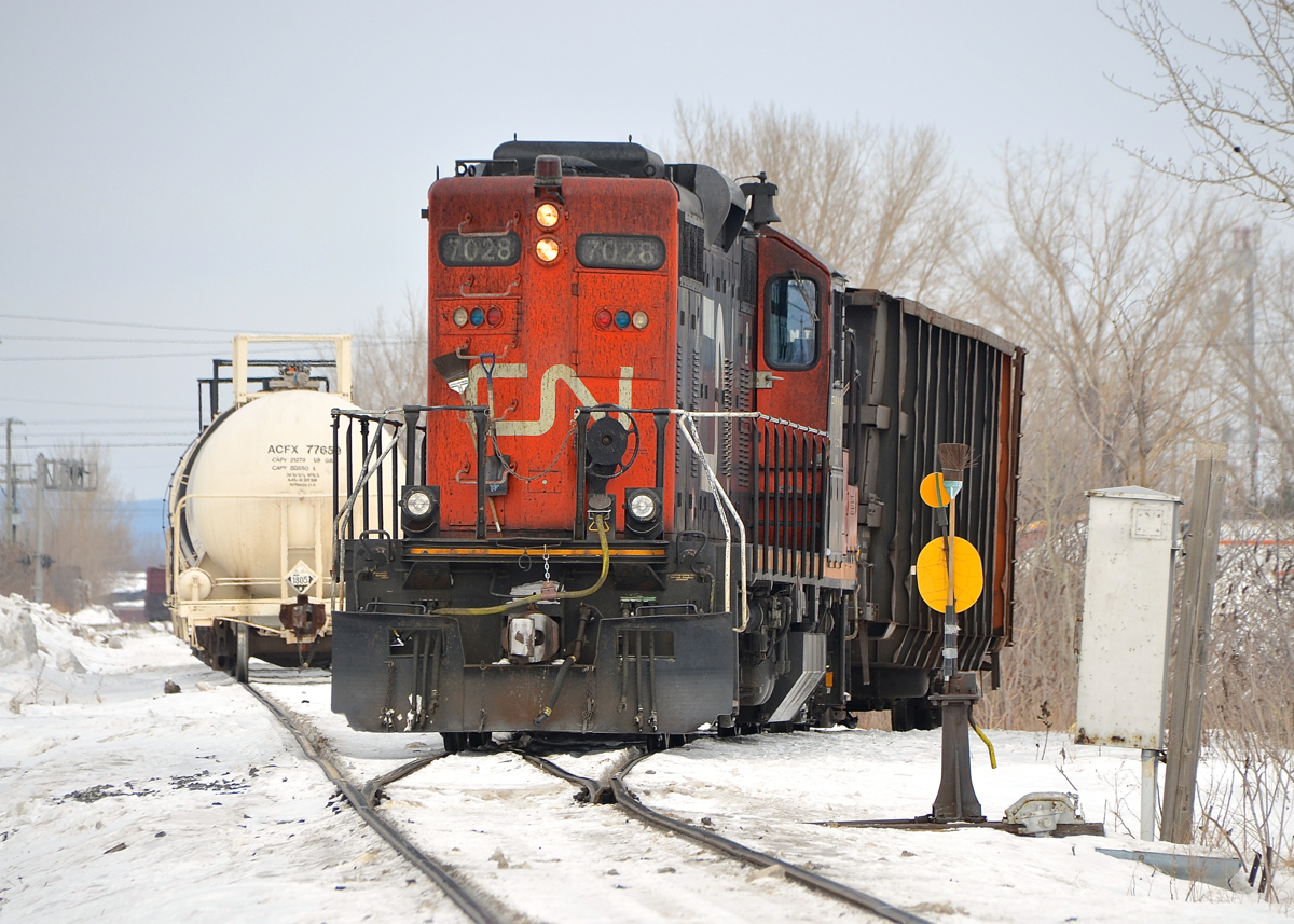 CN's Massena Spur currently extends from MP 84 in Brossard, Qc on Montreal's South shore (where it joins the Rouses Point Sub) to MP 77.3. It currently terminates just short of CP's Adirondack sub (it used to cross it near CP's Delson station), but this line was once the Massena sub and extended all the way to Massena, NY. There are some industrial clients remaining on the line, and yesterday CN 527 (which normally is a transfer from Southwark Yard to Taschereau yard in the Montreal area) was called to head down the Massena spur to serve some clients on this rarely photographed line. Here CN 7028 is doing some switching on the spur towards Brasseur Transport.