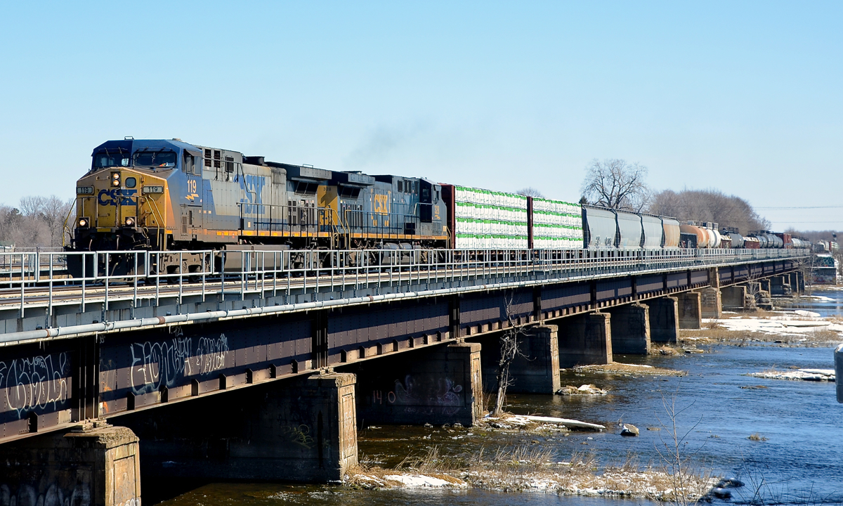 CSX power on CN 327 again. CN 327, the daily train from Montreal to Huntingdon for interchange with CSX once ran with CSX power most of the time, but ran with CN power for much of 2014. However CSX power is now seen a bit more often on this train. Here CN 327 with CSXT 119 and CSXT 328 crosses the Ottawa River as it leaves Montreal behind.