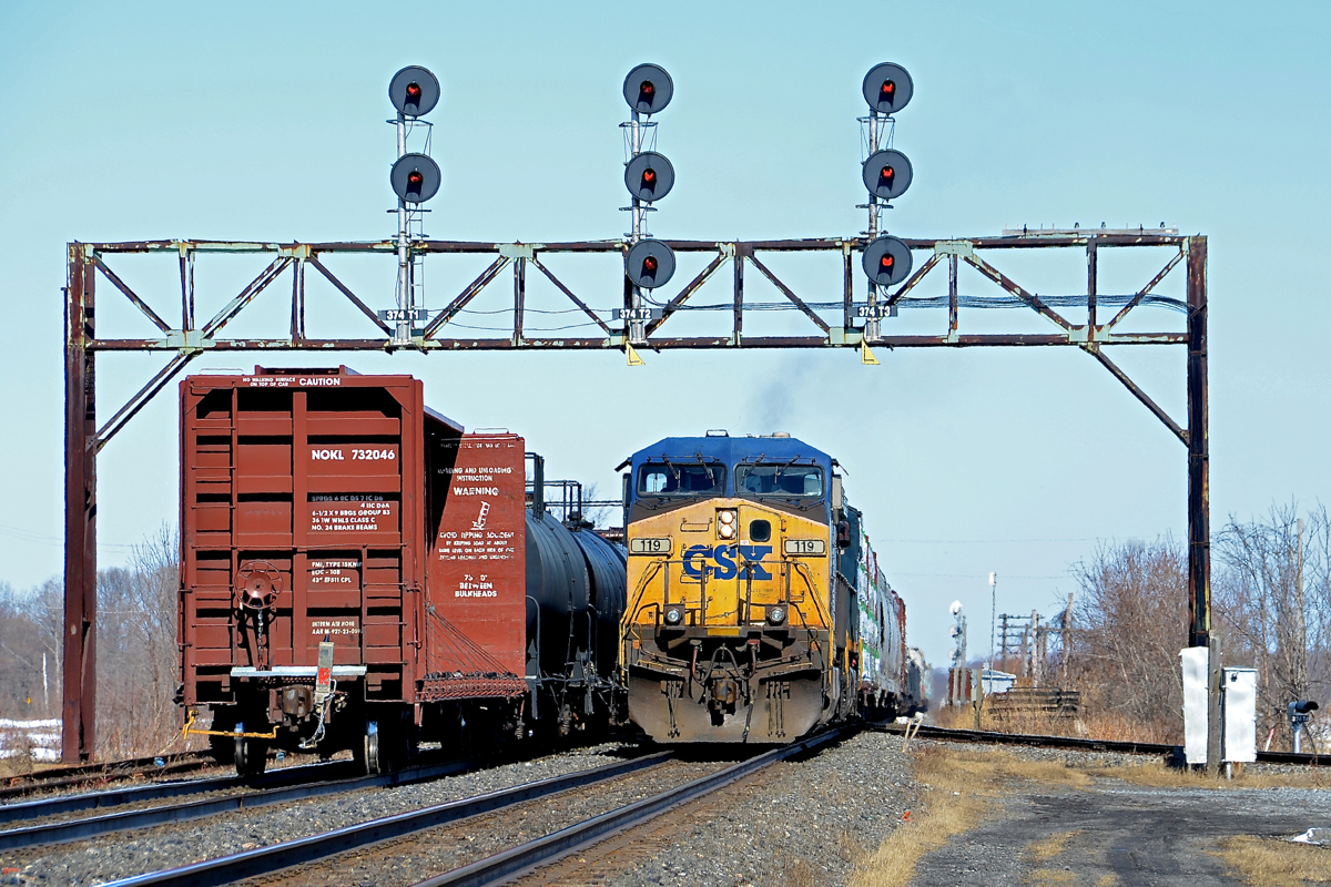 CN 327 with CSXT 119 and CSXT 328 is backing up on the Kingston sub so that it can head south on the Valleyfield sub (seen at right). Passing at left is CN 368.