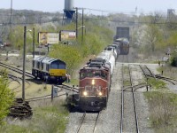 The last pair of a Nedrail (Netherlands) order for ten JT42CWR (EMD Class 66) locomotives are test run on the Trillium Railway in May 2006.  ITS Rail assembled the locomotives under subcontract to EMD, at the ITS Rail plant in St. Catharines, ON.  The locomotives wait in Merritton yard for a Hamilton bound CN freight to clear so they can cross the Grimsby Sub and head south towards Thorold.   Its unusual to see equipment built to the smaller European loading gauge alongside the somewhat larger North American rolling stock.  In the background, a Niagara bound train crosses the bridge over the Welland Canal. 