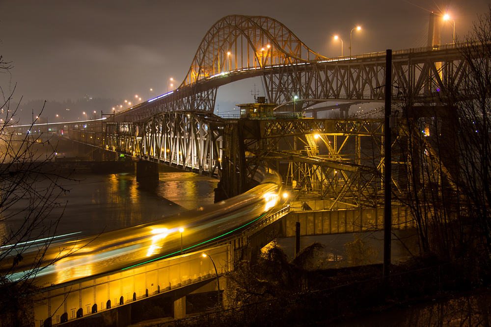 Its the last day of 2013 and Via Rails Canadian is seen streaking southbound across the historic Fraser River Bridge towards CNs Thornton Yard and points east. The bridge is a major junction point, connecting New Westminster and Surrey and sees rail traffic from CN, CP, BNSF, SRY, Amtrak, Rocky Mountaineer and Via. 

Towering above the Fraser River Bridge is another historic and important crossing, the 78 year old Pattullo bridge, which is the subject of a proposed more modern replacement bridge. To the right, behind the Pattullo gives a brief glimpse of one of the Skytrains bridge spans.