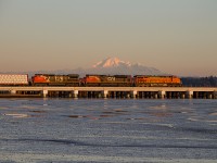 On a nice, sunny Sunday evening southbound VBCEVE (New Westminster, BC - Everett, Wa) crosses the newly decked portion of the Mud Bay trestle, with Mount Baker being highlighted by the evening light. The trestle, which was originally wooden, has fallen victim for the need to be upgraded as an increase of heavier BNSF coal traffic has become more frequent to Roberts Bank Coal Port.  
