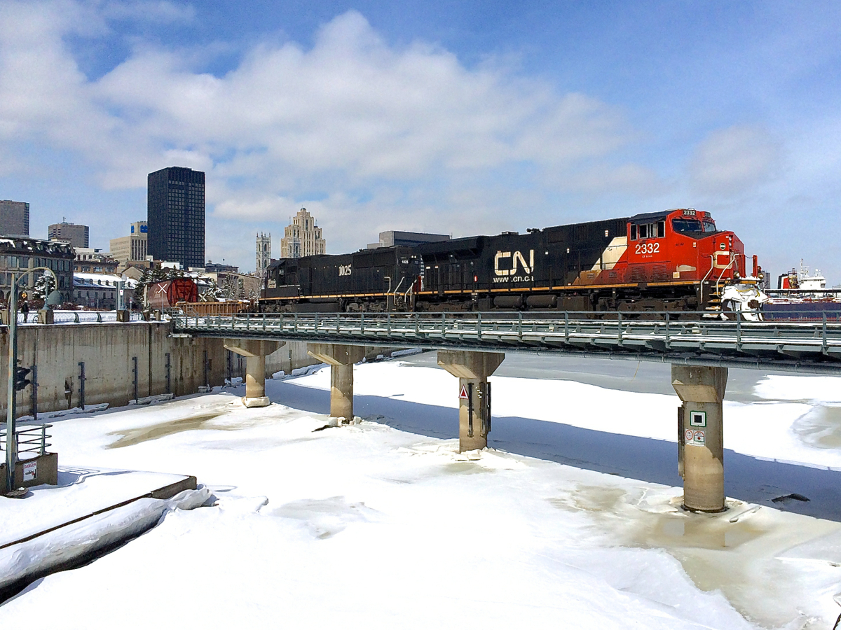 CN 527 takes a detour. CN 527 with CN 2332 and IC 1025 is taking a detour from its usual Southwark Yard-Taschereau Yard run to bring back a long string of empty grain cars out of the Port of Montreal. Here it is crossing the Lachine Canal.