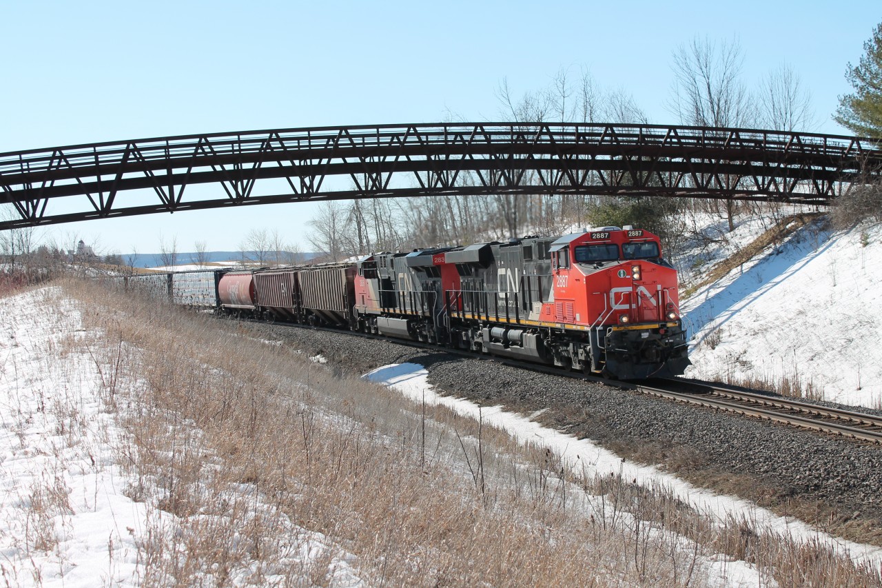 CN 2887 leads CN 2836 through the Halton Sub pulling a mixed load of freight. CN 2944 was midway through pushing as well. All 3 power look like they came from the paint shop. Glencairn Golf course club house peaks through over the top of horizon.