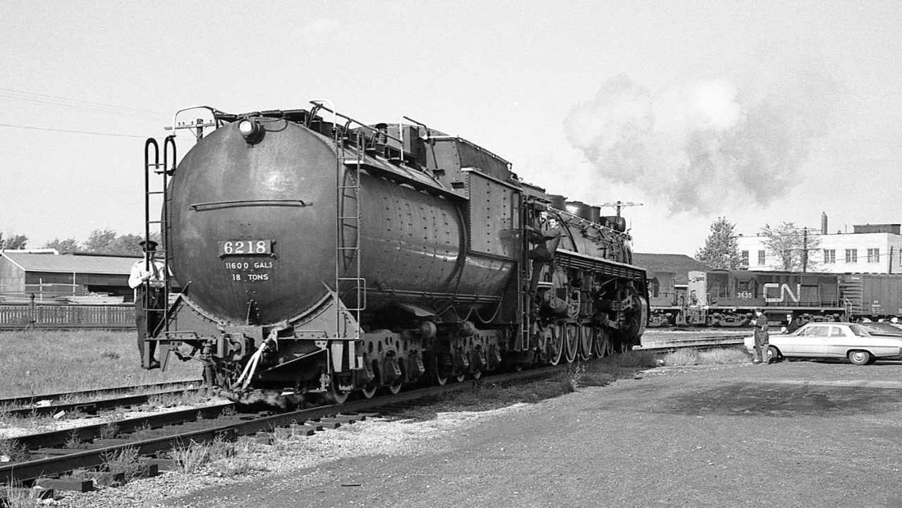 1965 steam excursion in London and 6218 backs in the shop track for coal & water. They will later return to the depot downtown for their train and depart eastward on the Dundas Sub.
Very little of this scene remains today, only the white building on the right and the mainline itself (note westbound on main in background). The entire roundhouse facility is gone and now is a sports recreation center.