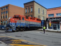 GEXR Train 581-08 making a rare daylight appearance on the Waterloo spur (Kitchener to Elmira). Due to the construction of the Light Rail Transit line, called "ION" - using the Waterloo spur from this point northward (Town Square station to Northfield station) a Welded Rail Train was brought to town. The drop was managed by GrandLinq, the consortium overseeing construction and operation of the line. This sleepy railway will be transformed into LRT over the next two years. The train dropped rail all day on Saturday, finishing on Sunday by the early afternoon. In this scene, Waterloo Regional police, who were escorting the train across all crossings, is seen flagging traffic, the train is reversing and the power is about to duck between king st buildings.<br><br>Due to LRT construction, freight trains are restricted from 2300-0500 and daylight moves are by far and large very very rare. Once the LRT is open daylight freights will be history. <br><br>More interesting facts: Think of the LRT as a double track line with three one-way single track loops in downtown Waterloo and Kitchener (<a href=http://rapidtransit.regionofwaterloo.ca/en/projectinformation/system.asp target=_blank>click here for map)</a>. The Waterloo single track section will use Caroline Street (yes - the same Caroline St in the famous CP/Grand River Railway street running - abandoned 1994 - it's coming back!) and King St (Also coming back - once used for Streetcars from the Kitchener Waterloo Railways - abandoned 1946) for the in-street portion of the LRT.  To reach king st, a curve will be right where I am standing (approx) to join the Waterloo Spur to my left through the Town Square Mall trackage. The Waterloo spur from this point where the locomotive is and south (to right through the buildings) will remain a freight only line and used for new Flexity deliveries. <br><br>A new layover facility complete with loop tracks is presently being built at Northfield Drive in Waterloo to store and maintain the Bombardier Flexity LRT cars (exact same as TTC, just blue, and standard gauge). Rails for this yard are part of this drop. The LRT will run all the way to Fairway mall near Cambridge, from there change to BRT to Cambridge. The route is too complicated to type here, maps can be found on the ION website - this LRT project will transform Waterloo Region and will be a bellweather for other LRT projects in Canada. More details: http://rapidtransit.regionofwaterloo.ca