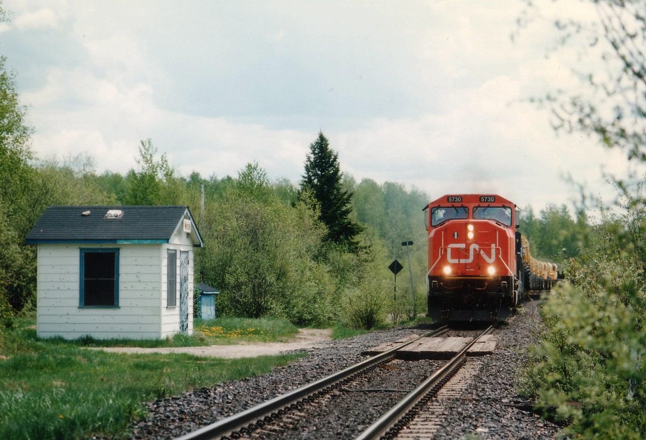 En route to Englehart from Cartier, I passed a turnoff to Westree while on 560 heading east. Knowing the CN went by there, I thought I should check for a shack by the track, or rather, a station. So I turned around and headed in. Route 560A proved to be nothing but dirt and ruts, certainly nothing that resembled a highway but more a logging road at best. And I wasn't really prepared for this "community". First thing I saw after the 10 KM drive in was a dilapidated dive of a general store,carport on the side with empty beer cases piled higher than the roof. (The government dairy must make very infrequent stops here). The 15 or so scattered 'houses' were a depressing sight, and thru the main dirt intersection I went towards the tracks. And my gawrsh!! There is the station !! Not much, but it had a name on it. No sooner I had taken a photo than I heard a northbound train coming around the lake. Growth was right up to the tracks so I really had nowhere to go. The resulting photo was taken with the train barreling down on me around 50-60 mph and I jumped back as soon as I shot this. There was a second unit, CR 6000 and a string of school bus cabs that you can just make out in the photo. A rather large Duchabani Lake (on the right) had a handful of decent looking cottages on it; otherwise this place, 18 miles south of Gogama, was a write-off. Looking around, I decided the only "industry" in this place was fishing and drinking beer. And I left.  Since I am a sucker for out of the way dumps like this, I did revisit a couple of years later and a lot of homes, as well as the 'station', had been leveled. So this shot is a part of history. In case there are any residents of Westree (ha ha ha) on RP.ca., the opinions expressed are soley those of the photographer.
