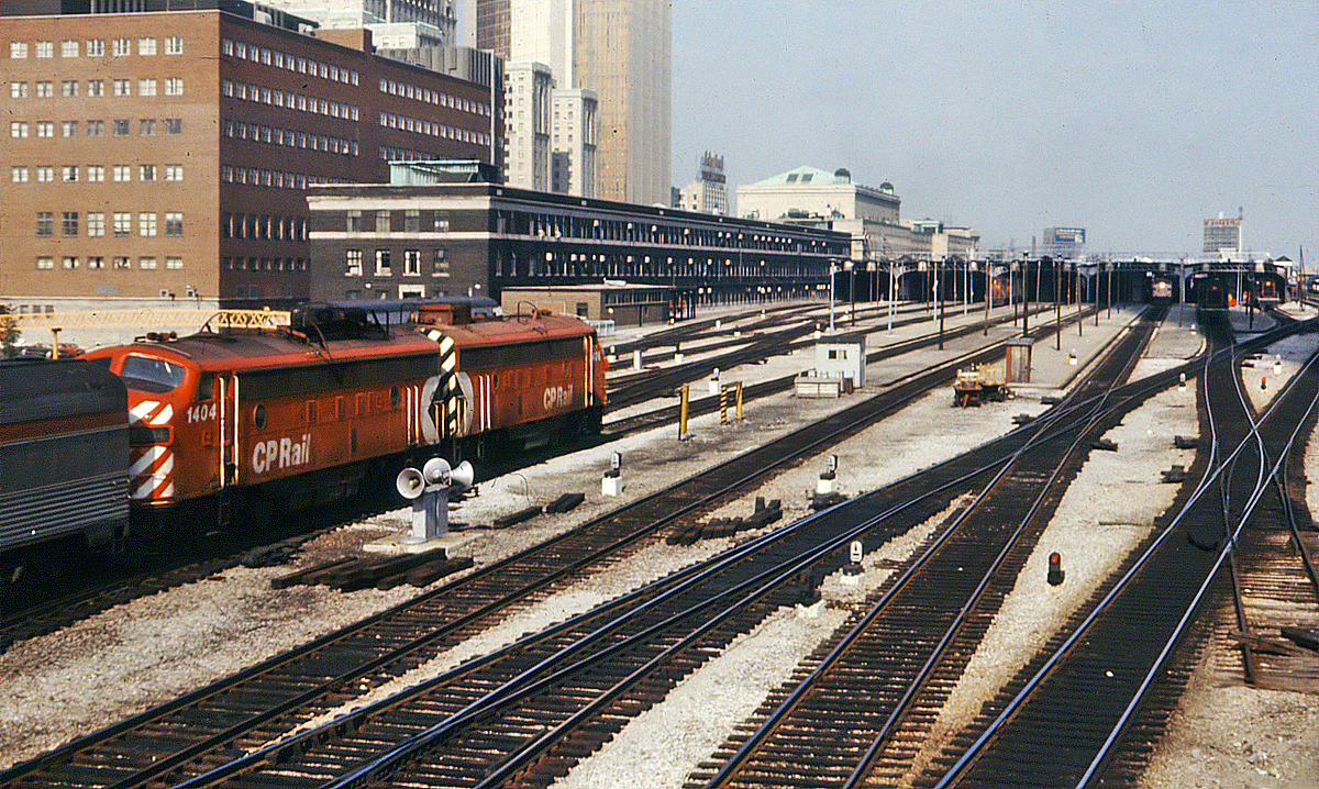 A late running Canadian arrives as it partner prepares to leave. Also a couple of GP9's on a westbound, and an ALCO switcher preparing to head back to the coach yard. The date is just a guess
