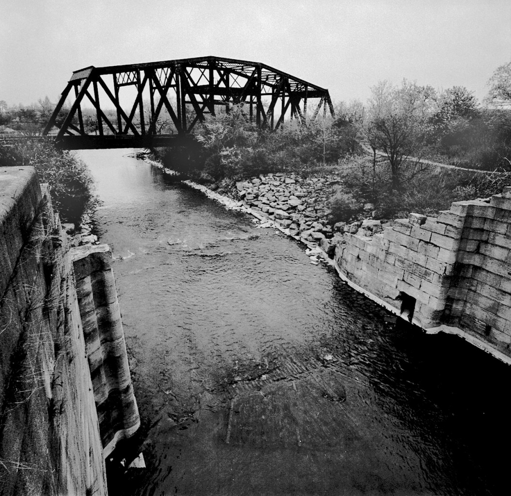 At about mile 8 on CN's Grimsby sub is Iron Bridge, an old swing bridge over a disused section of the Welland Canal. The bridge dates to the 1890's, in the foreground are the limestone block walls of Lock 17 of the third Welland Canal, built in 1887.