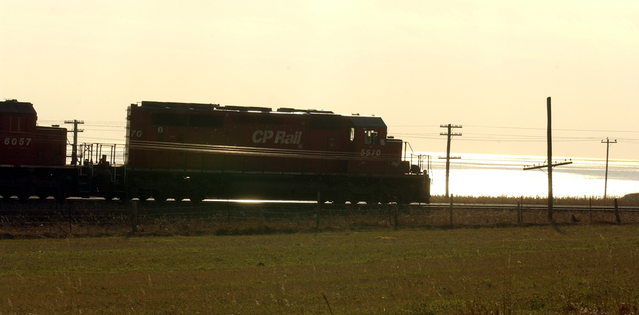 The late autumn sun reflects off Lake Ontario backlighting a westbound CP Rail freight led by an SD40.