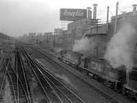 On a murky evening in 1978, a CN freight train with MLW power heads west past Fort York in this view from Strachan Avenue.  The train is about to cross the Wharf Lead that led south from Parkdale to the waterfront, originally the old Toronto, Grey & Bruce Ry. narrow gauge mainline to the Queens Wharf.  On the north side of the tracks is the old Inglis plant, on the left is the CNE siding.  