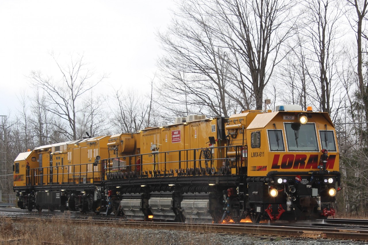 The Loram Rail Grinder sends sparks flying as it works on the rails at the Campbellville Rd crossing just East of Guelph Junction. Cold, snow, rain, and sleet are all helping to keep the track side dead grass from catching fire.