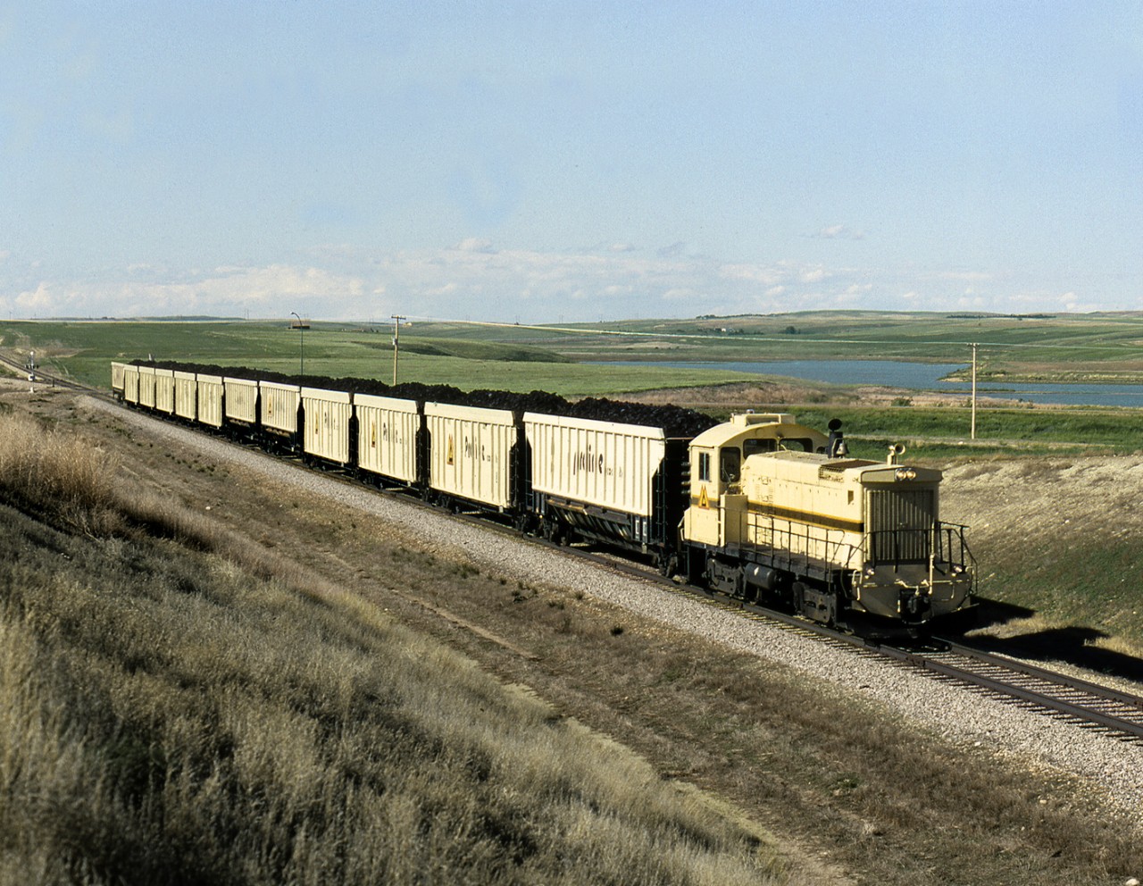 Prairie Coal's SW1001 84160 with southbound coal approaches highway 18 on the 5 mile line from the strip mines south to Sask Power's Poplar River generating station east of Coronach.