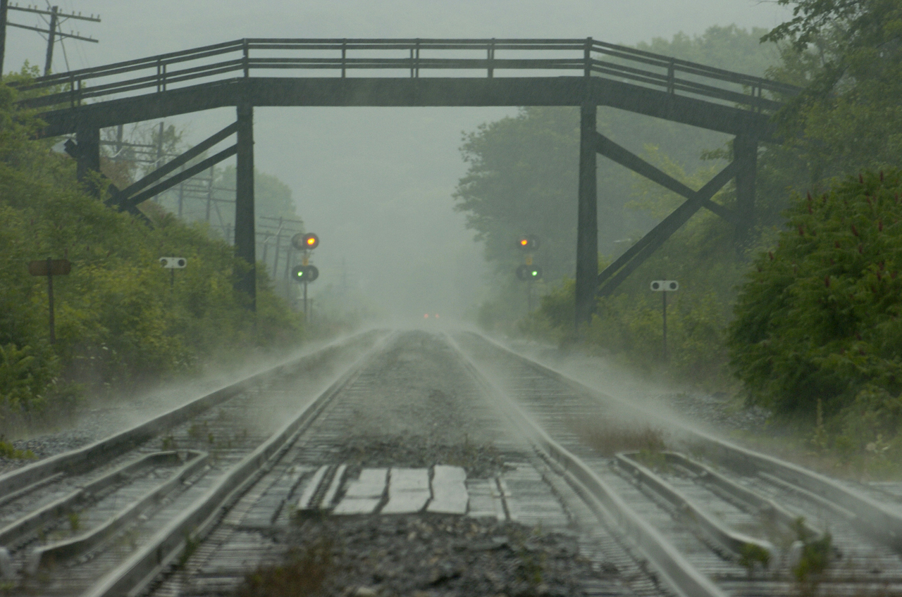 After a heavy midsummer downpour the CP tracks going under the farm crossing and down the Niagara escarpment are shrouded with mist, looking east from the Canyon Road grade crossing.