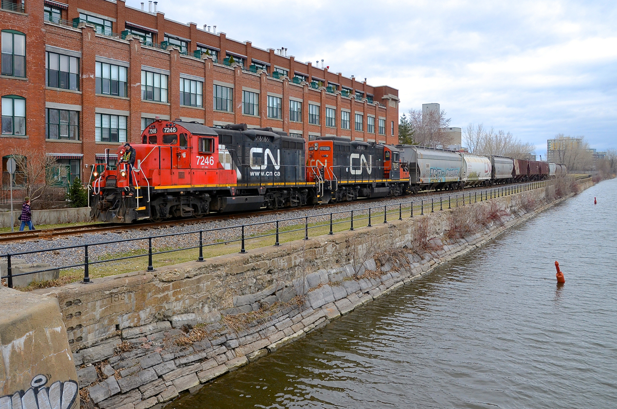 Once Canada's busiest industrial area, the Lachine canal used to be lined with railways on both sides serving numerous industries, like the building here, which was Stelco, and is now condo's. Here a CN switcher with CN 7246 & CN 7015 returns from dropping cars off at Robin Hood Flour mill (visible middle right, behind the trees), the only customer left in this area.