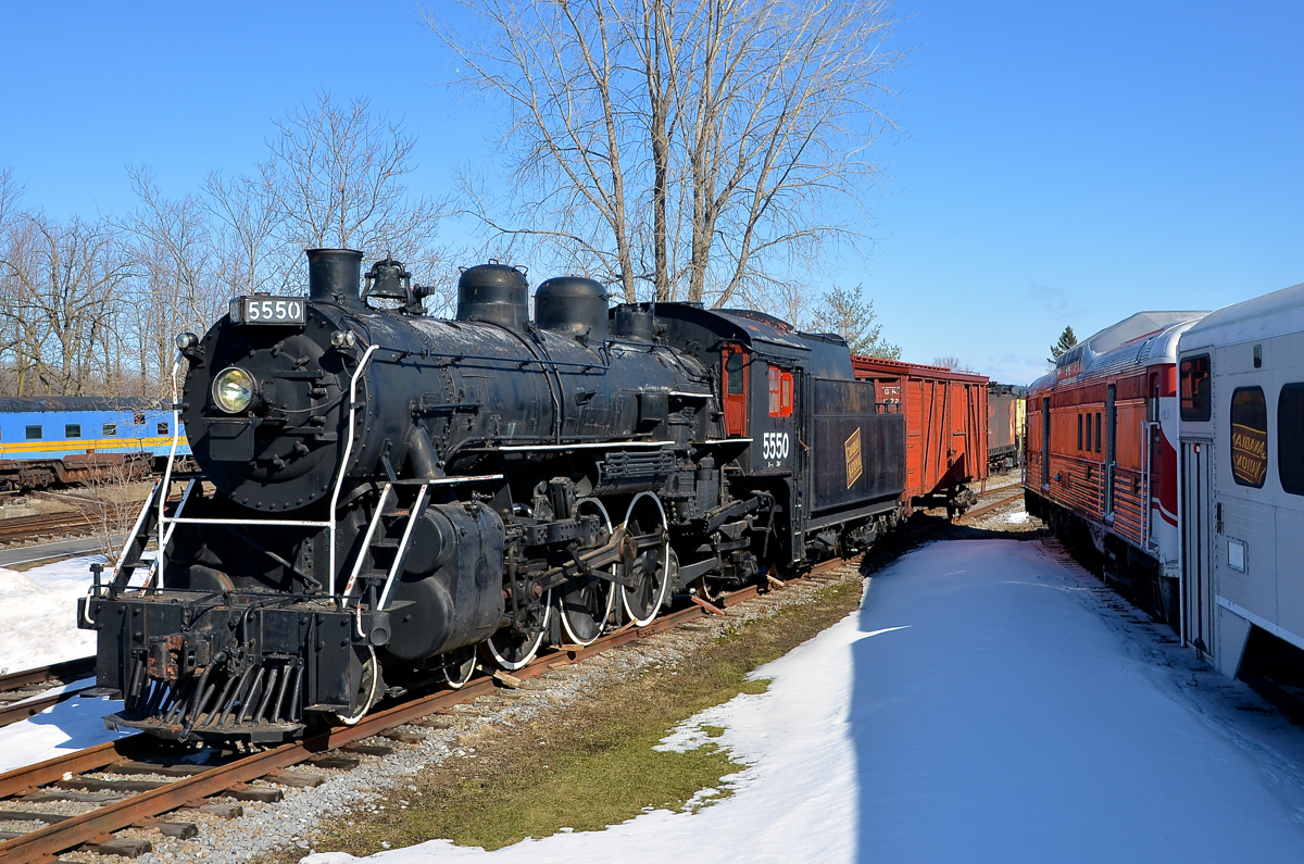 CN logo reflecting off an old GO Transit car. CN 5550 is a 4-6-2 built by Montreal Locomotive Works for the Canadian Government Railways in 1920. The CGR was absorbed into CN soon thereafter, where it was renumbered to 5550 and became part of Class K-2-b. The engine was removed from hangar 5 at Exporail last fall and spent the winter under a tarp. The tarp has been removed, allowing the logo on the tender to reflect off the GO Transit car at right.