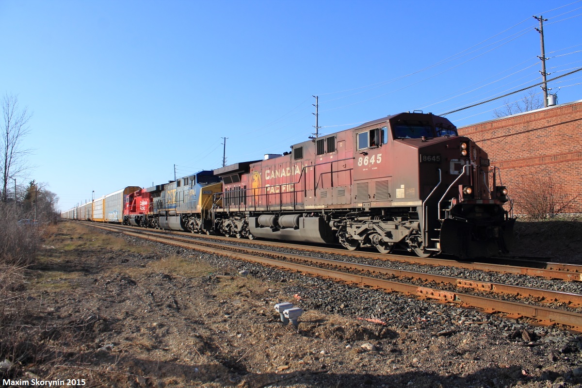 On April 12th of 2015, we traveled to Streetsville, Ontario to see Canadian Pacific train #244 with a CSX Transportation unit sandwiched between a CP General Electric AC400CW and a GMD GP20C-ECO locomotive. The shiny apple red GP20C-ECO, has been freshly rebuilt and re-painted from older SD40-2 models that are becoming rare to come across. Here, the train is pictured passing the Thomas Street railroad crossing on its way to CP's Toronto Yard