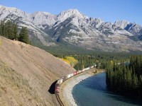 The clouds that loomed around earlier in the day have cleared up and the sun shines bright on the Massive Mountain range, as CP 9728 shoves on the tail end of an eastbound grain train. 