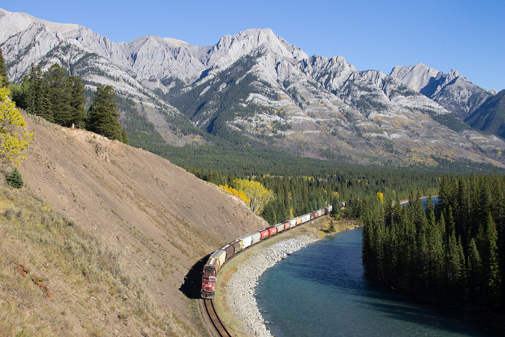 The clouds that loomed around earlier in the day have cleared up and the sun shines bright on the Massive Mountain range, as CP 9728 shoves on the tail end of an eastbound grain train.