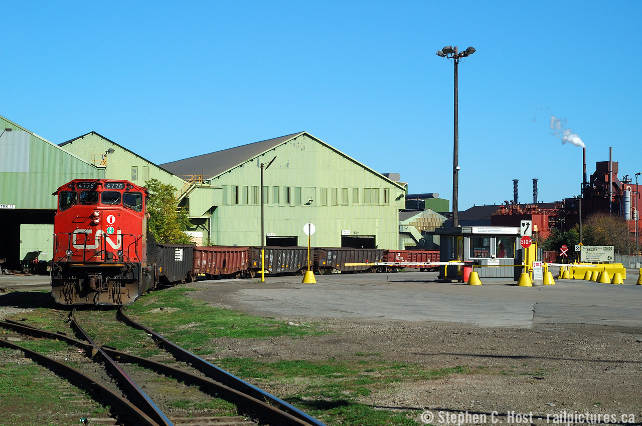 The Southern Ontario Railway, with leased/assigned CN 4776 rounds the curve by the guard shack at Stelco with a cut of NS family gondolas filled with steel billets. At the time of this photo, Stelco was going gangbusters pumping out raw steel while US Steel had for all intents bought the plant, the deal still in the closing phase. US Steel share price at the time of this photo (during acquisition)? Nearly $100. Today? $20