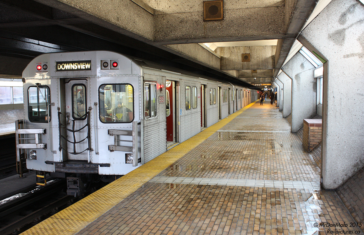 It's a rainy day in the city as a set of Bombardier T1 subway cars pause at the Toronto Transit Commission's Eglinton West subway station on the trip south on the Spadina Line. It's even wet in the subway - water pools on the north side of the platforms, probably blown or leaking in from the open section just behind us. Cars from the nearby Allen Expressway (on either side of the subway line) can be heard swishing past on rainy pavement...well, at least on the northbound side; the southbound traffic is perpetually choked at the Eglinton Avenue West exit.

To add a little spice to the system compared to its previous utilitarian and functional stations (that some compare to public washrooms because of the spartan nature and tiling), in the 1970's the TTC approached a number of architectural firms to design stations along the new Spadina subway line, which opened in 1978. Eglinton West was designed by Arthur Erickson Architects and featured the a mix of concrete, brick, dark earth tones, sharp edges and windows lining the platforms, heralding the transition from bright outdoor open cut subway line to subterranean underground tunnels south of Eglinton. Art installations were also featured at each station, and Eglinton West is known for its large "Summertime Streetcar" mural work by Gerald Zeldin at the south end of the platforms.