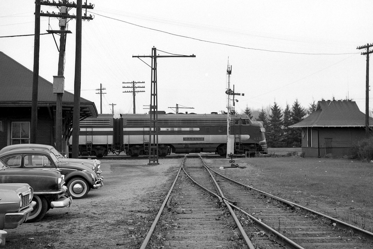 Wabash F7A 671 crosses the St. Thomas diamond with the London & Port Stanley Railway, heading eastbound on CN's Chatham-Cayuga Subs in 1967. A selection of vintage automobiles are parked next to the old Wabash/GTR station on the left, and semaphore signals guard the interlocking from movements on the L&PS.This location, known on the timetables as St. Thomas, was the transition point from Mile 0.0 CN Chatham Sub to the west, to Mile 119.0 CN Cayuga Sub to the east, both formerly Grand Trunk lines (that the Wabash had running rights over) and originally built as the Great Western Railway's "Canada Air Line". The L&PS crossed this junction point north-sound at the diamond pictured. They were taken over in 1965 by CN and the line became the CN Talbot Sub and later Talbot Spur (the diamond here was Mile 15.0).For more rail action in St. Thomas:A L&PS passenger excursion at their station: http://www.railpictures.ca/?attachment_id=13531L&PS passenger train hauling freight:http://www.railpictures.ca/?attachment_id=13490A C&O train coming off the connector onto the CASO: http://www.railpictures.ca/?attachment_id=14920An NYC (PC) rail instection car pays a visit: http://www.railpictures.ca/?attachment_id=14921Chessie-painted C&O Geeps retired & stored: http://www.railpictures.ca/?attachment_id=14938