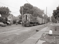 Trillium Railway 108 makes its way up the Townline Spur on its way to Interlake Paper, past a lady tidying her garden who doesn't give the train a second look.  The locomotive, a former CN S-13, built by the Montreal Locomotive works in 1959, is still active but the street running is no more.