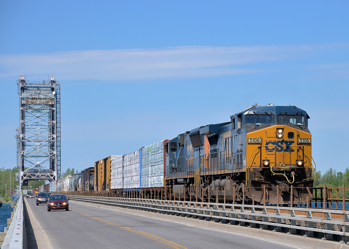 Trains and cars sharing the bridge. CN 327 with a pair of CSXT AC units (AC4400CW CSXT 5106 and SD70MAC CSXT 4817) crosses the Beauharnois canal on the Larocque Bridge which is used by both cars and CSXT (this is their Montreal subdivision). As can be seen in the distance this is a lift bridge, in fact both cars and CN 327 had been delayed by a boat just before.